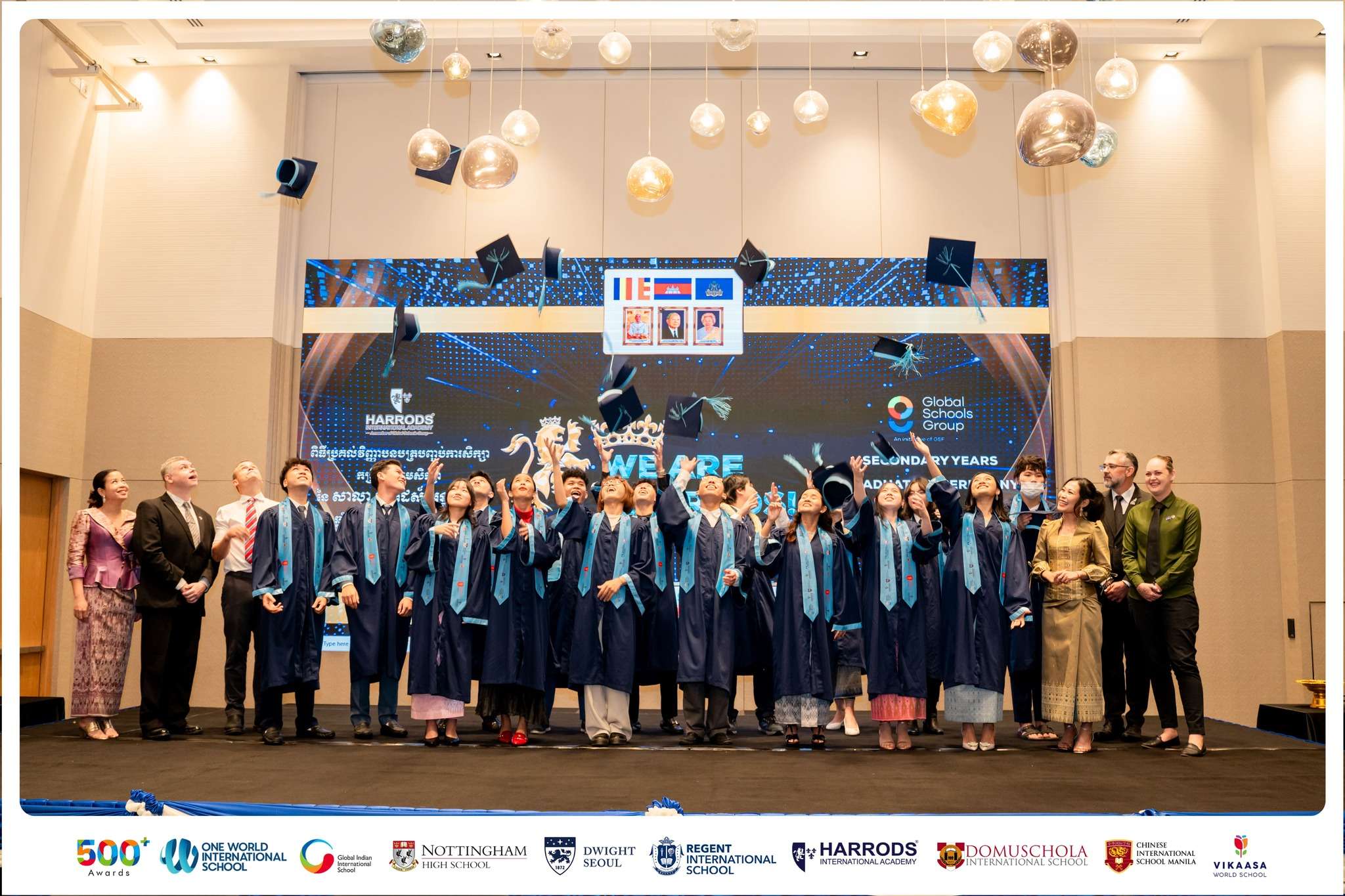 Harrods International Academy graduates posing on stage in blue gowns during the 2025 graduation ceremony.