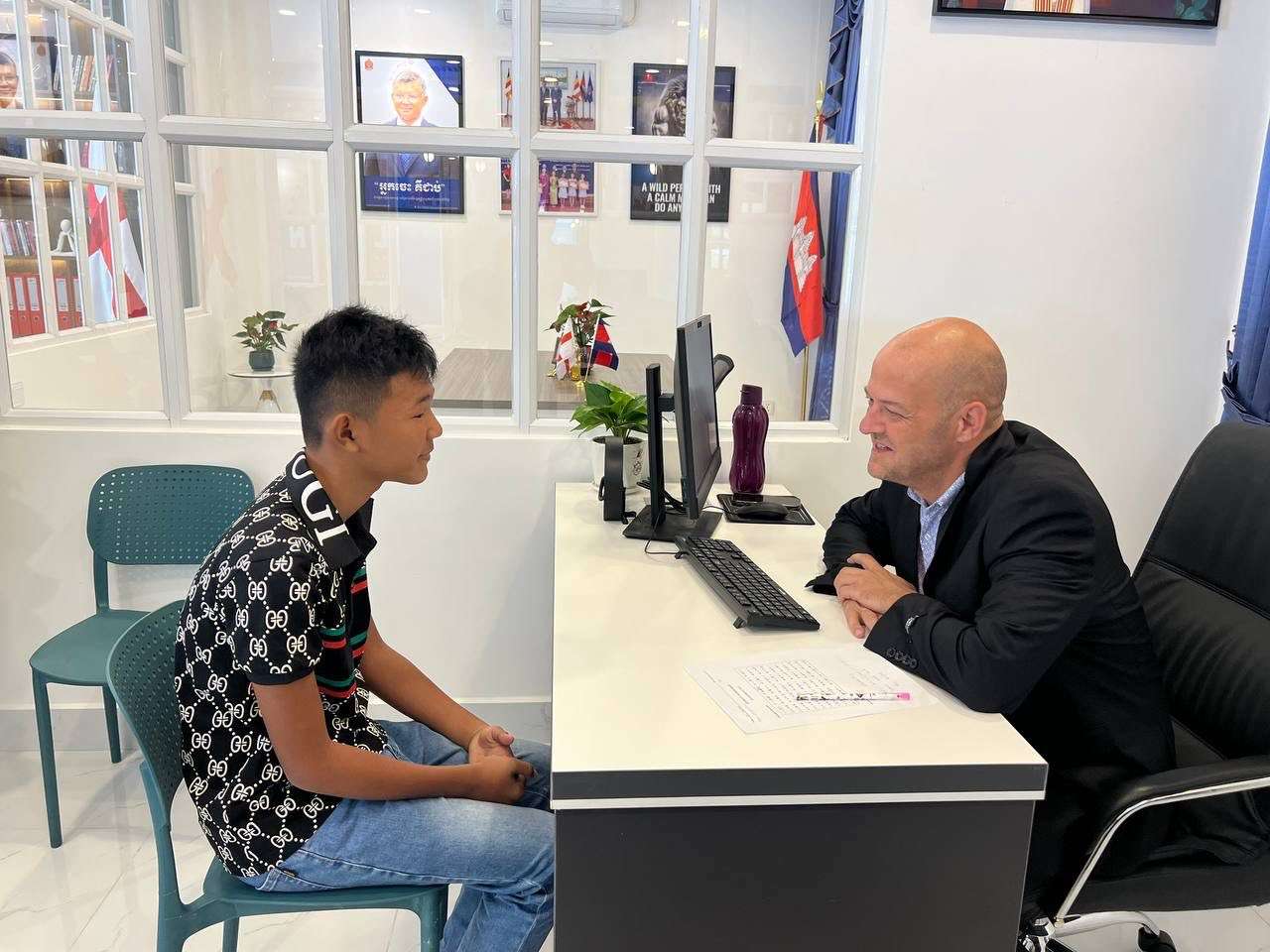 A Cambodian student sits across from a foreign instructor during a skills training session at True VISIONS International School of Cambodia, discussing career goals.
