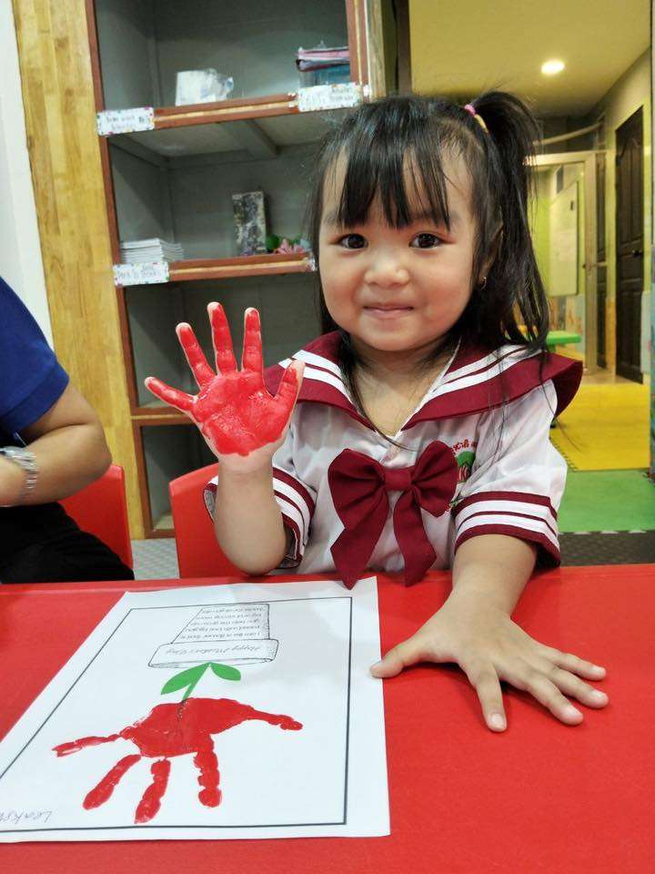 Young student showing painted red hands during art activity at HKC Tree International School