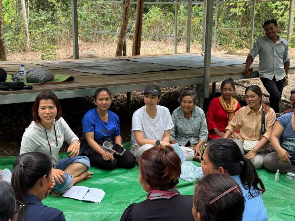 Women and community members participating in a grassroots discussion session organized by ActionAid Cambodia in a rural forest setting.