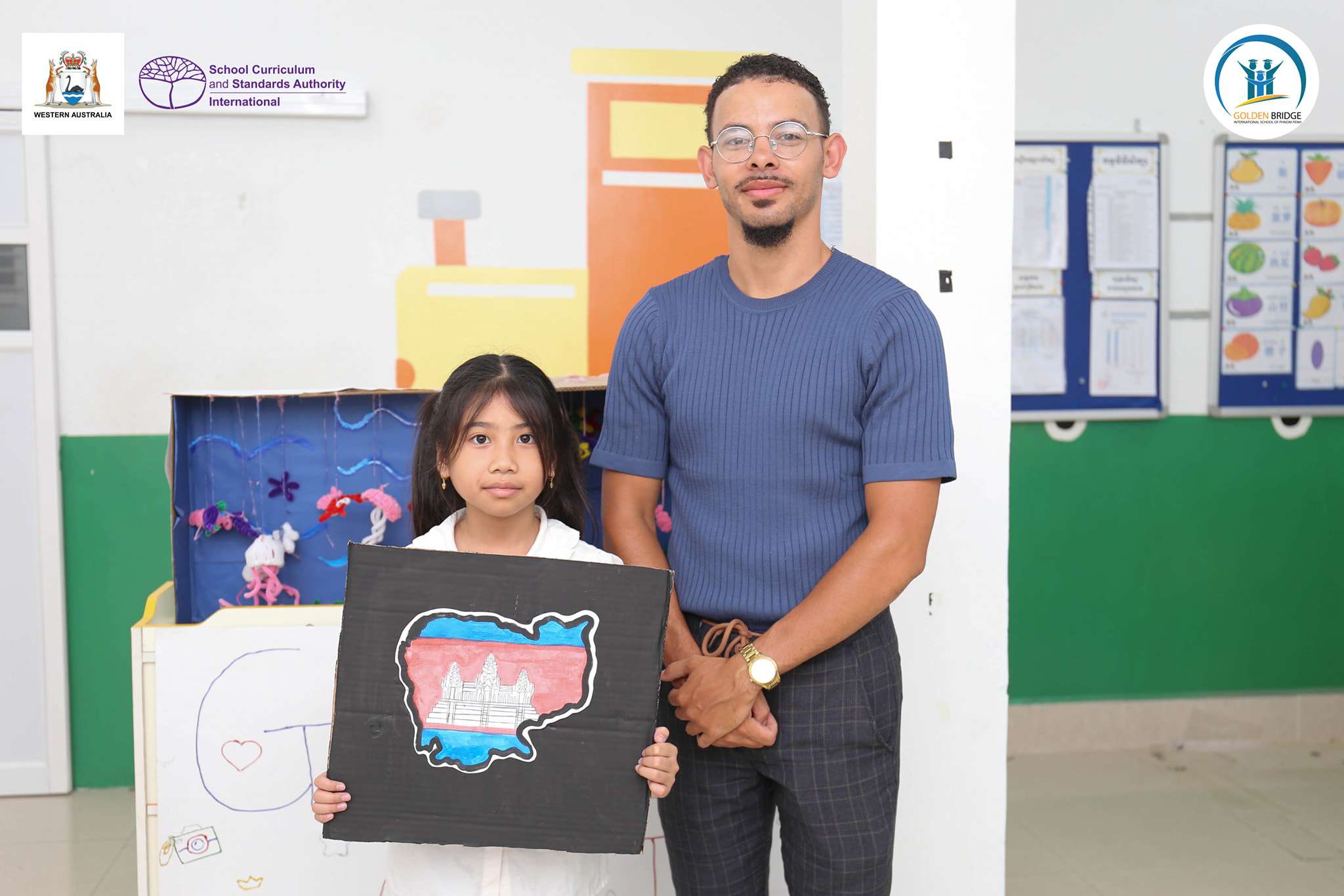 Students and an art teacher from Golden Bridge International School of Phnom Penh proudly displaying drawings and artworks during the 2025 Arts Exhibition
