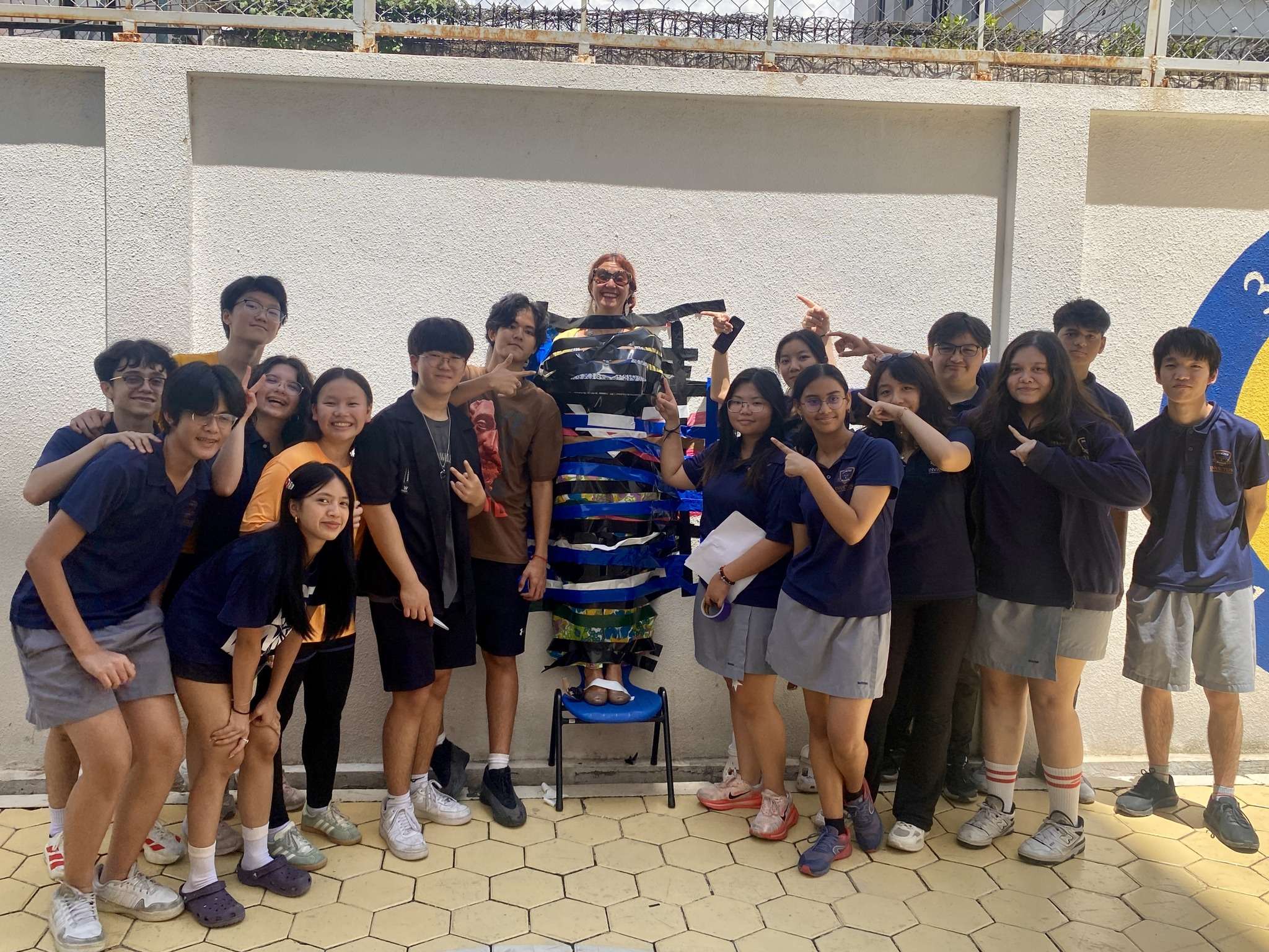 Group collage of Invictus International School Phnom Penh students and teachers during the “Wall for Charity” fundraiser, including scenes of educators taped to a wall, students cheering, and interactive moments