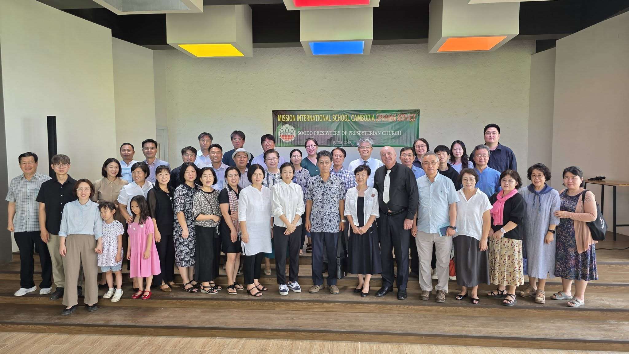 Group photo of Korean representatives and school leaders in front of the modern campus building of Mission International School Cambodia, taken during the opening service on July 8, 2025