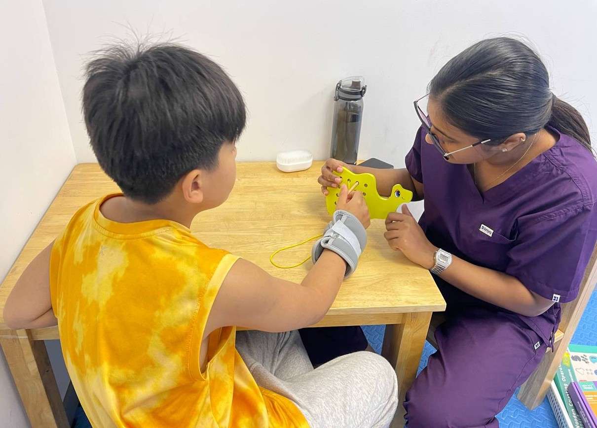 Occupational therapist at OrbRom Center in Phnom Penh working one-on-one with a child using colorful tools and fine motor activities in a structured setting