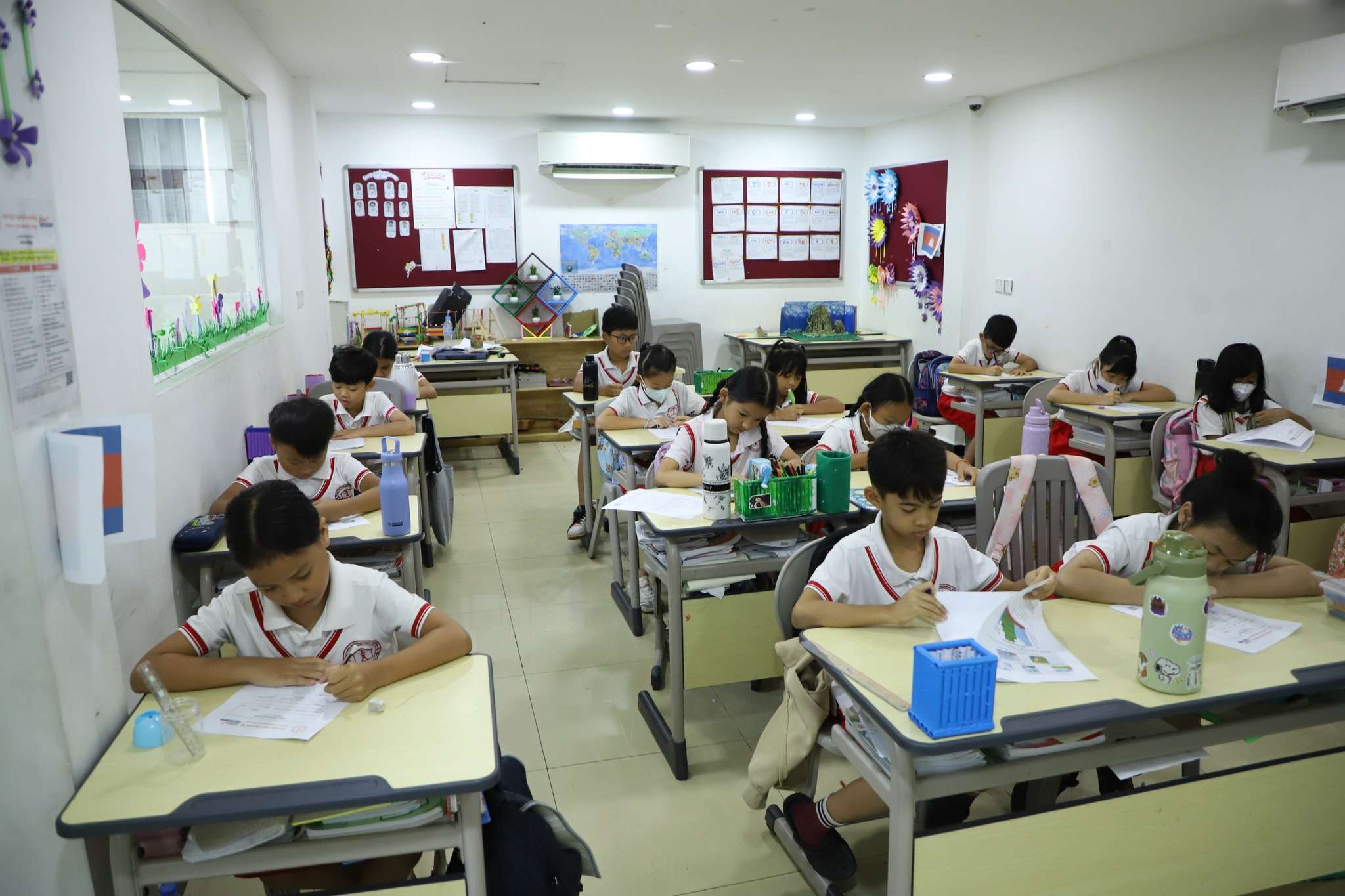Students at Ontario International School in Phnom Penh participating in classroom learning activities, writing and reading attentively at their desks