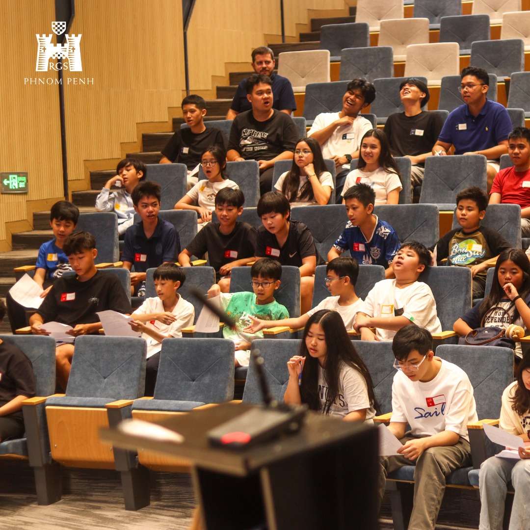 Students from Reigate Grammar School Phnom Penh participating in an Induction Camp session seated in a modern amphitheater-style classroom space.