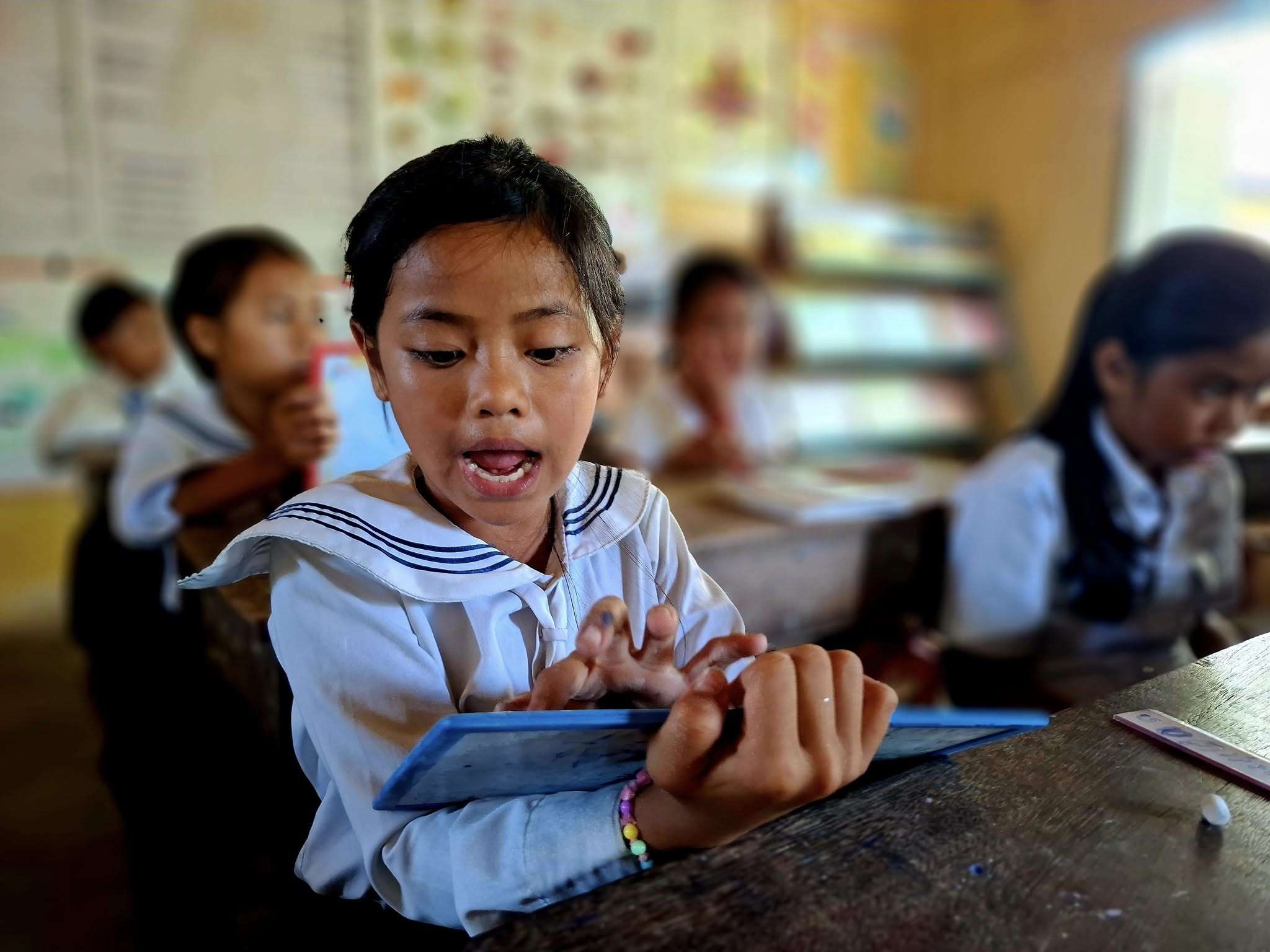 A Cambodian student in remedial class reading confidently after improving literacy skills, inspired to pursue a career as a nurse or doctor