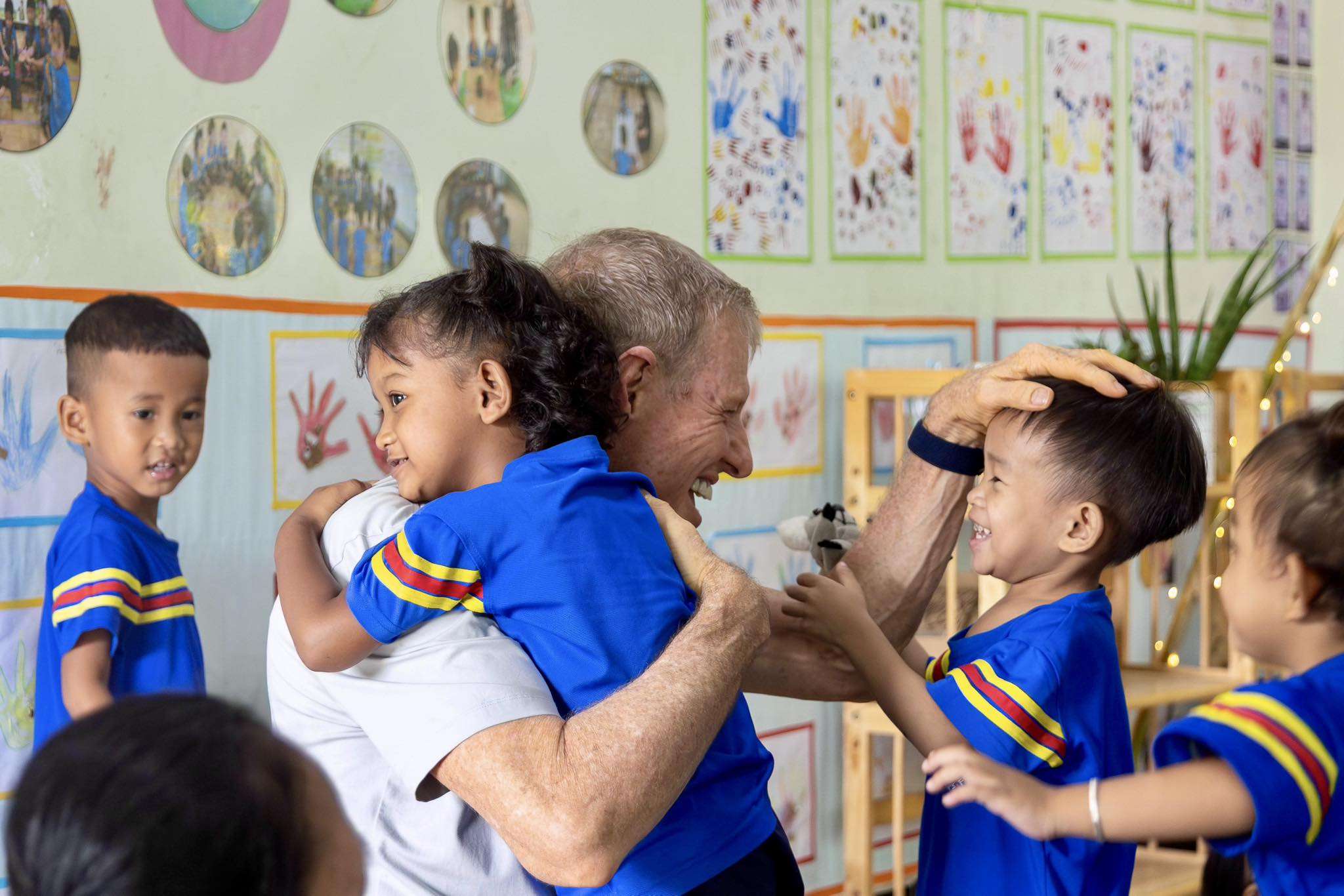 Children hugging an educator during Cambodian Children’s Fund kindergarten graduation celebration