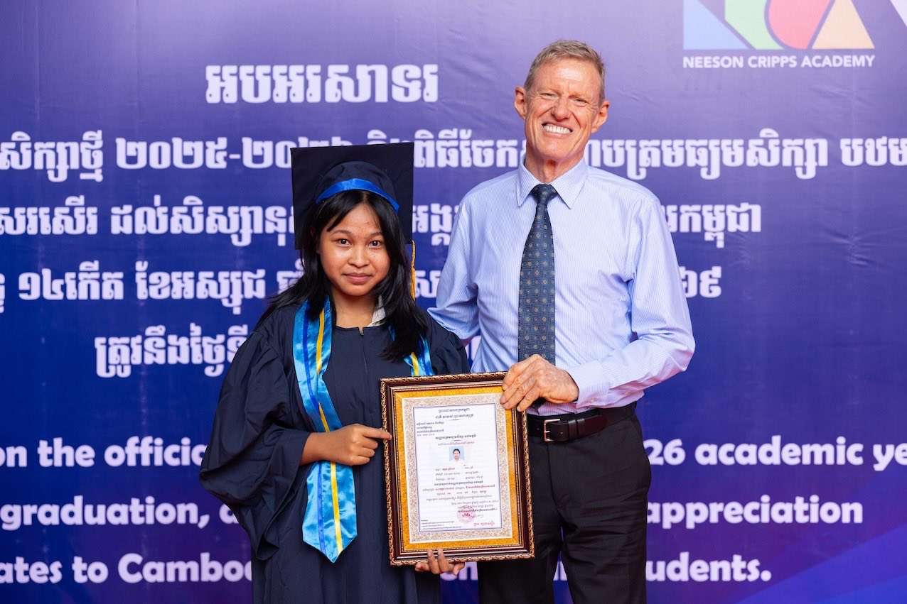 Student receiving a graduation certificate at Neeson Cripps Academy with a school representative.