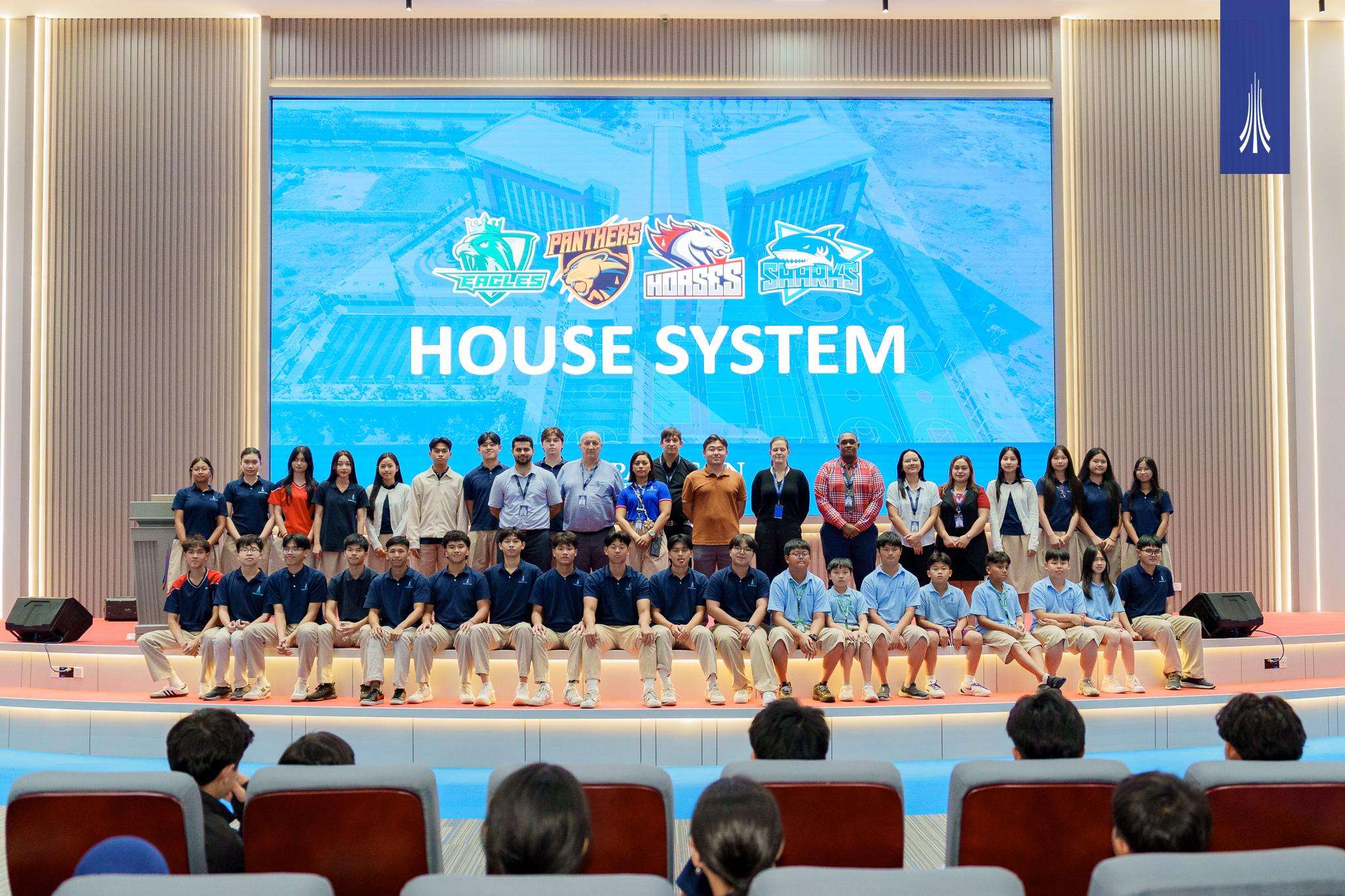 Students and staff at Paragon International School during the House System 2025 launch event, showcasing captains, masters, and house banners on stage.