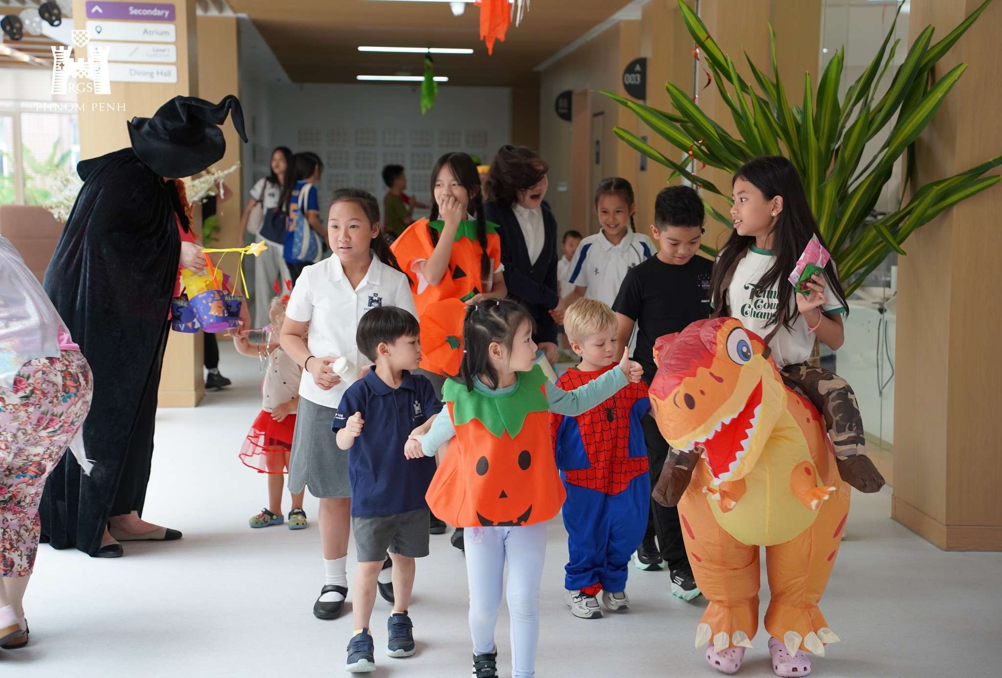 Students at Reigate Grammar School Phnom Penh celebrating Halloween in costumes on campus, engaging in activities such as dancing and trick-or-treating