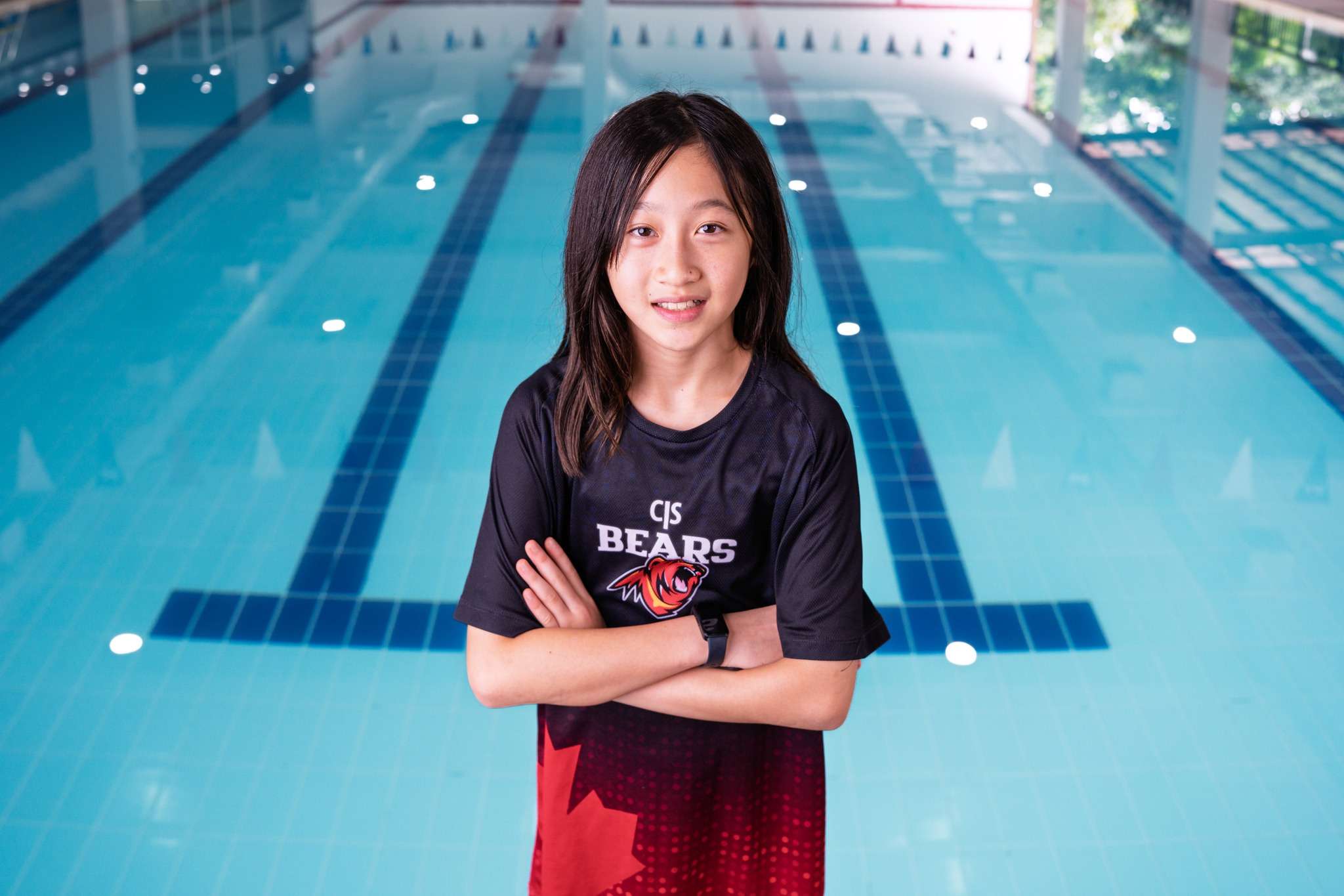 Three young CIS Bears swimmers standing poolside at Canadian International School of Phnom Penh after the PPAC8 swim meet.