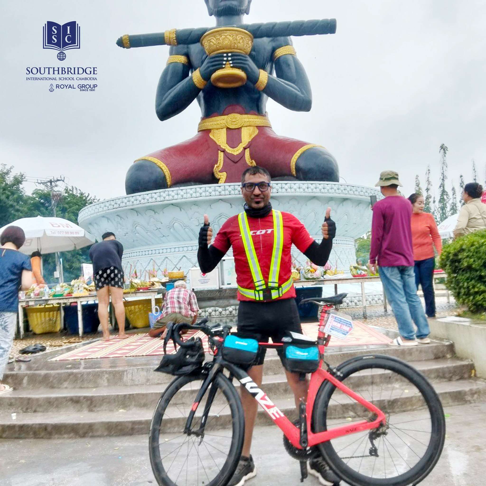 A cyclist from Southbridge International School Cambodia wearing a reflective vest poses with a road bike during a charity ride around Tonle Sap