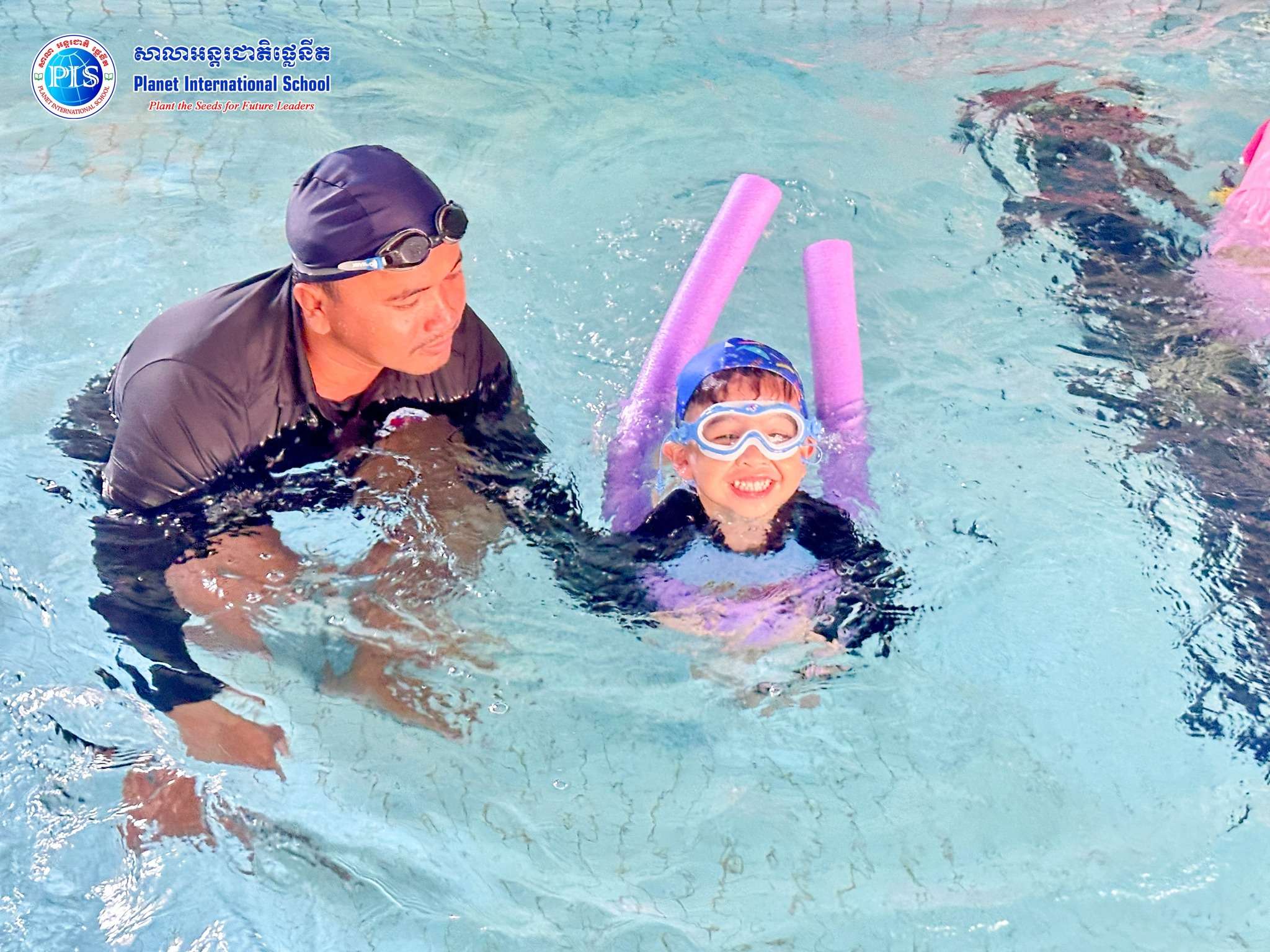 Children participating in supervised swimming lessons at Planet International School Chbar Ampov Campus, guided by instructors during water activities.
