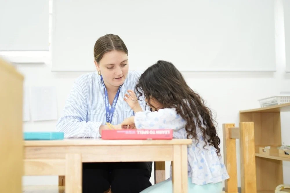 Preschool teacher supporting a young child during a structured learning activity in an inclusive classroom in Cambodia
