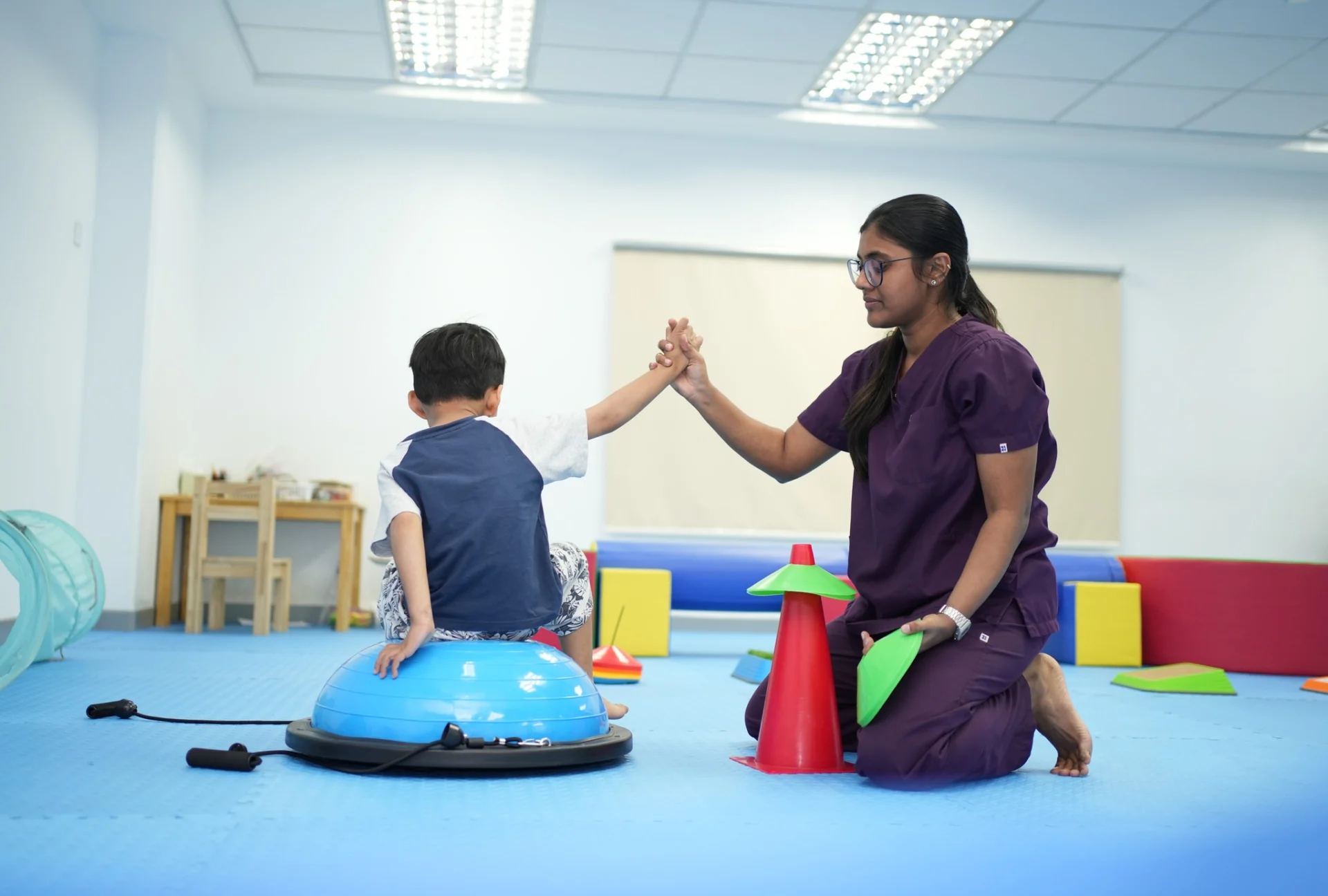 Occupational therapist guiding a child through balance and core strength activities during an occupational therapy session in Cambodia