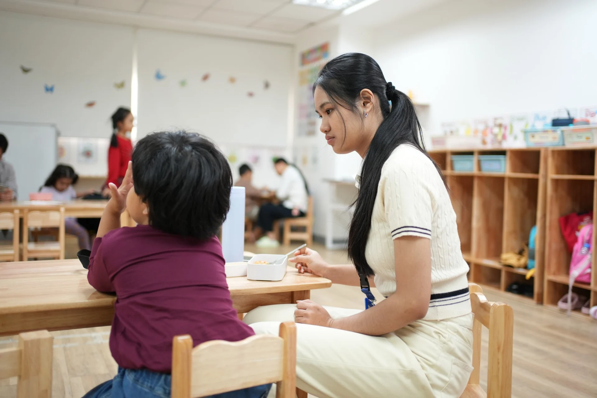 Teacher supporting a young child during a preschool learning activity at OrbRom Learning Support Center in Phnom Penh