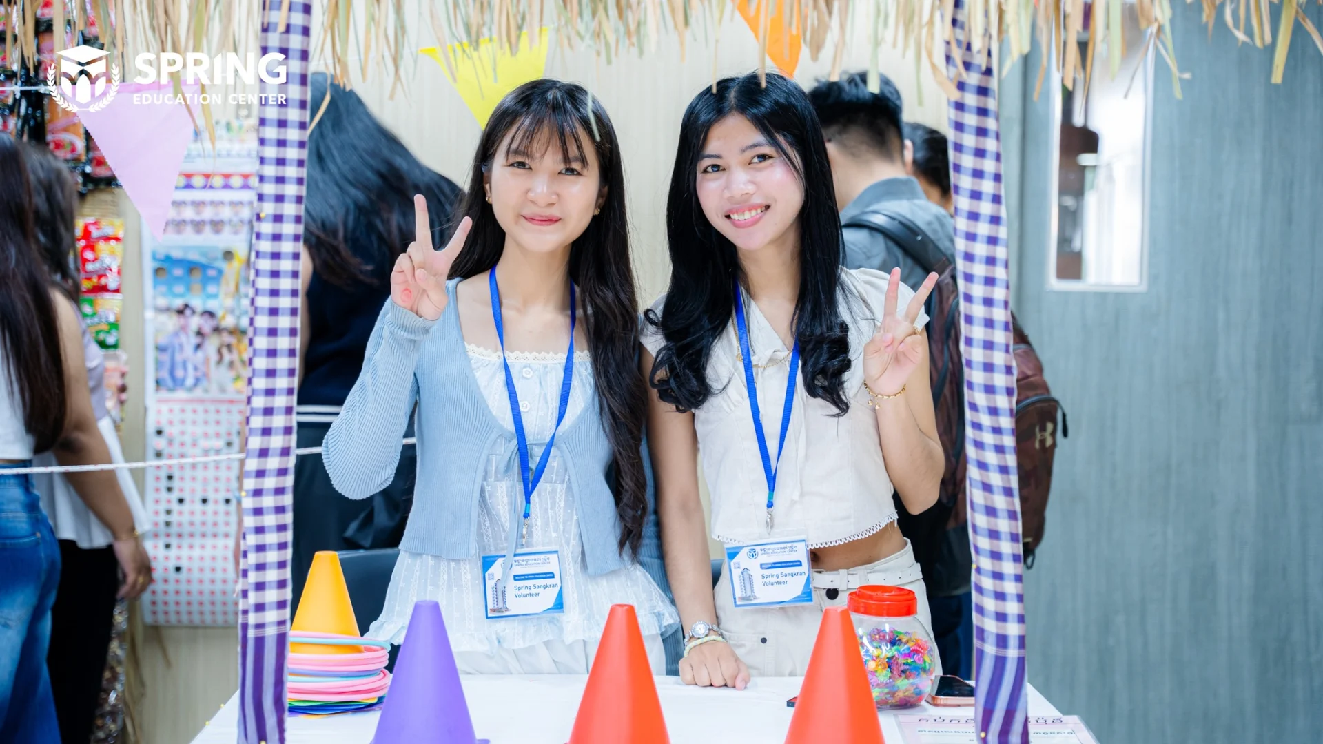 Students at Spring Education Center participating in Khmer New Year games including sack race and group activities in a school hall